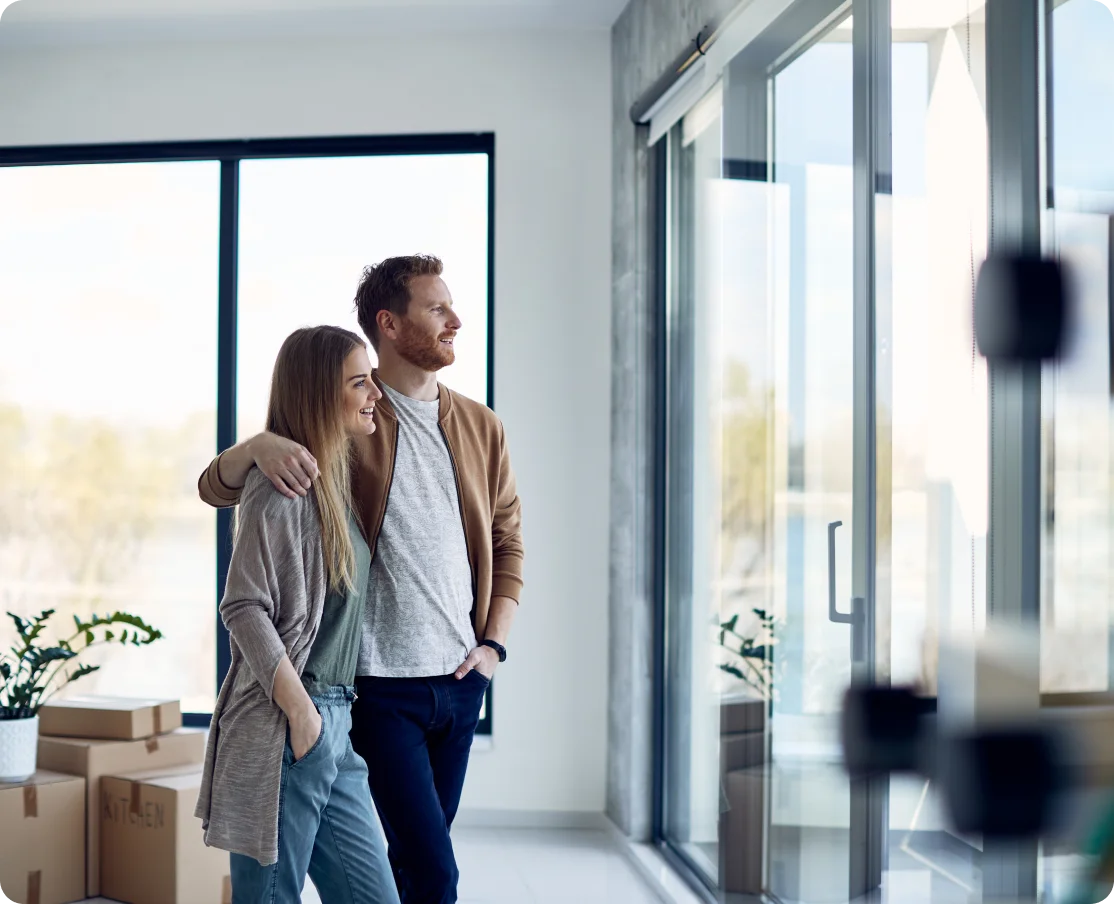 Happy couple looking out new home window.